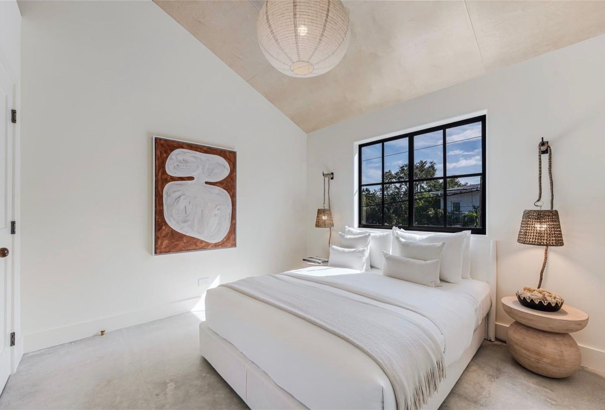 Primary bedroom with vaulted ceiling and terracotta artwork